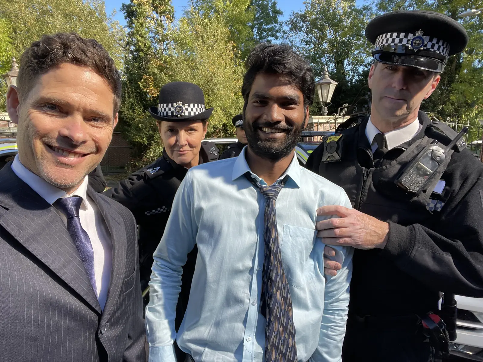 Alex Reece and Nikhil Vijay with fellow performers in police costume on the United Kacche location